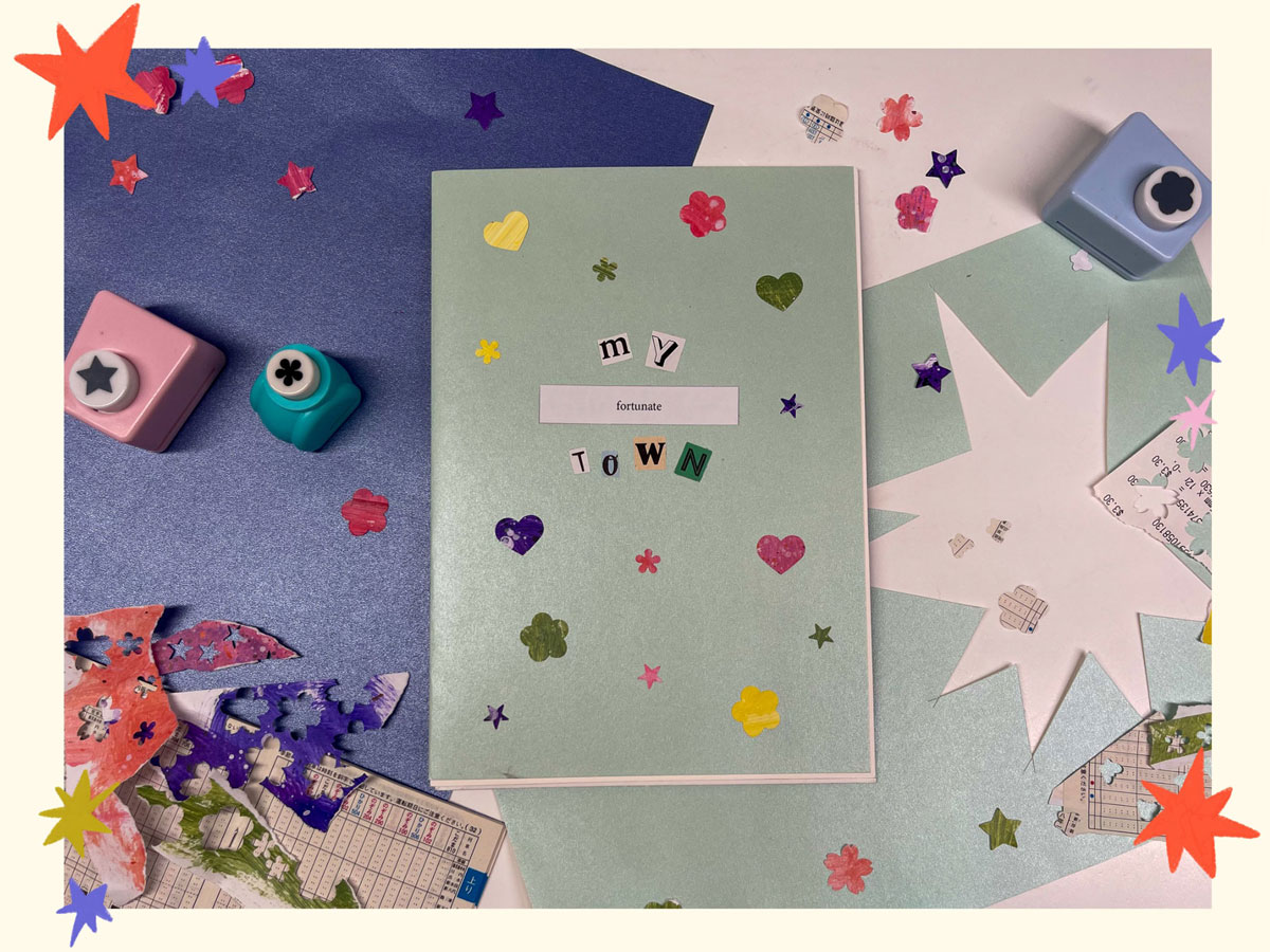 the cover page of a zine called 'my fortunate town' surrounded by the materials it is made with (pearl paper, painted collage paper, paper cut outs, train timetables)